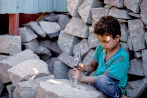 صورة موجعة لطفل في تعز يعمل في تكسير الأحجار لإعالة أسرته